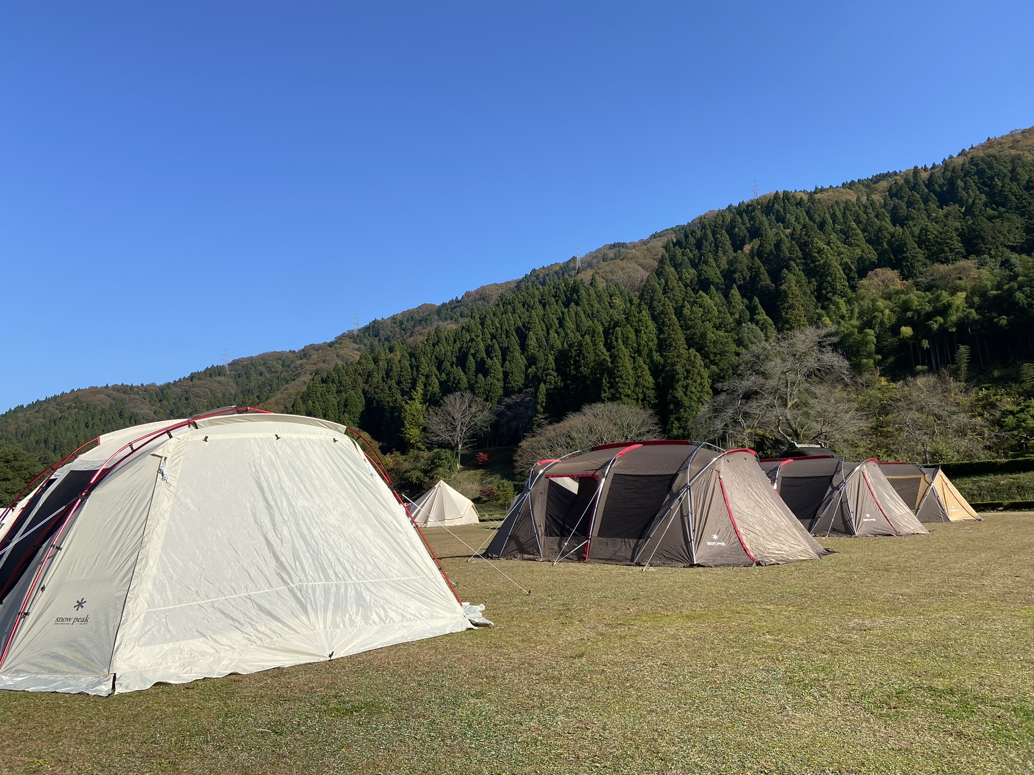 山に囲まれた会場へ並べたスノーピークの大型シェルターとテント