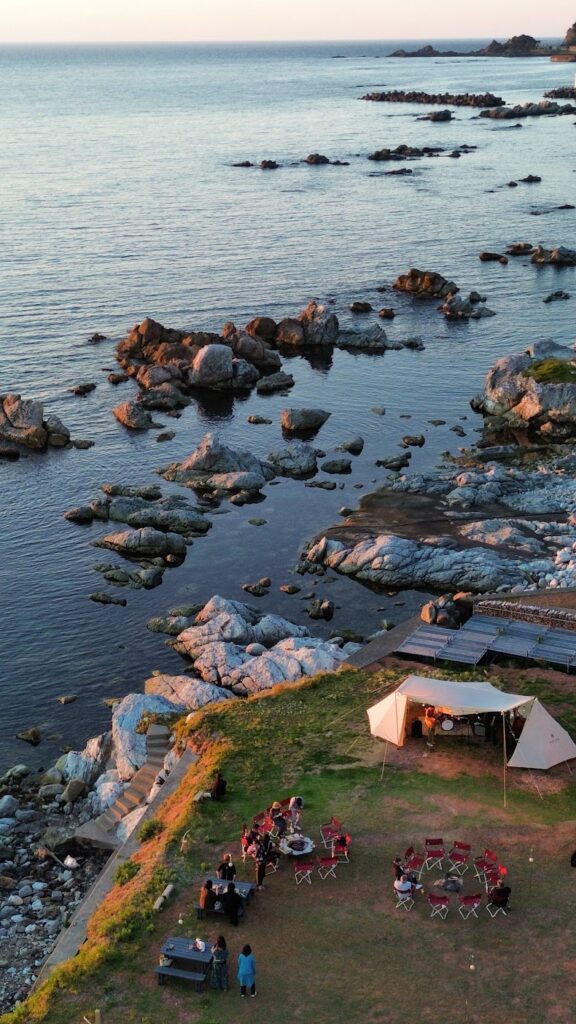 越前海岸の岩場と夕暮れの海、会場全体を見下ろす空撮写真
